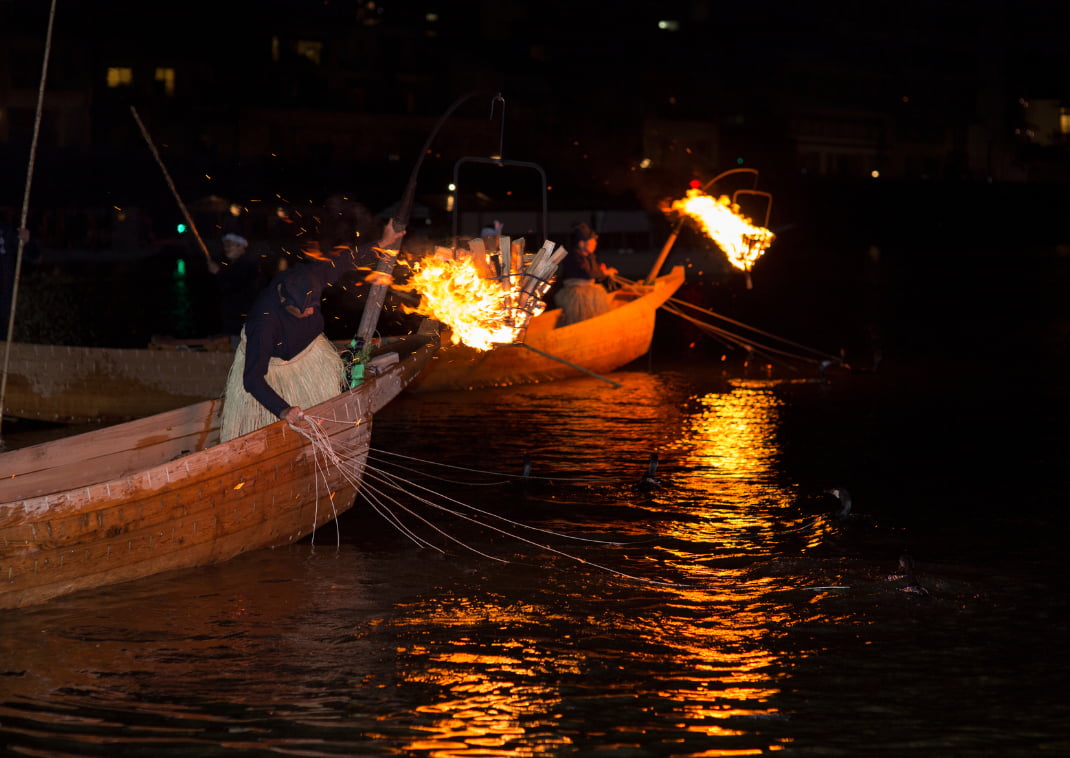 Japanske fiskere i både bruger fakler til traditionelt natfiskeri på en flod