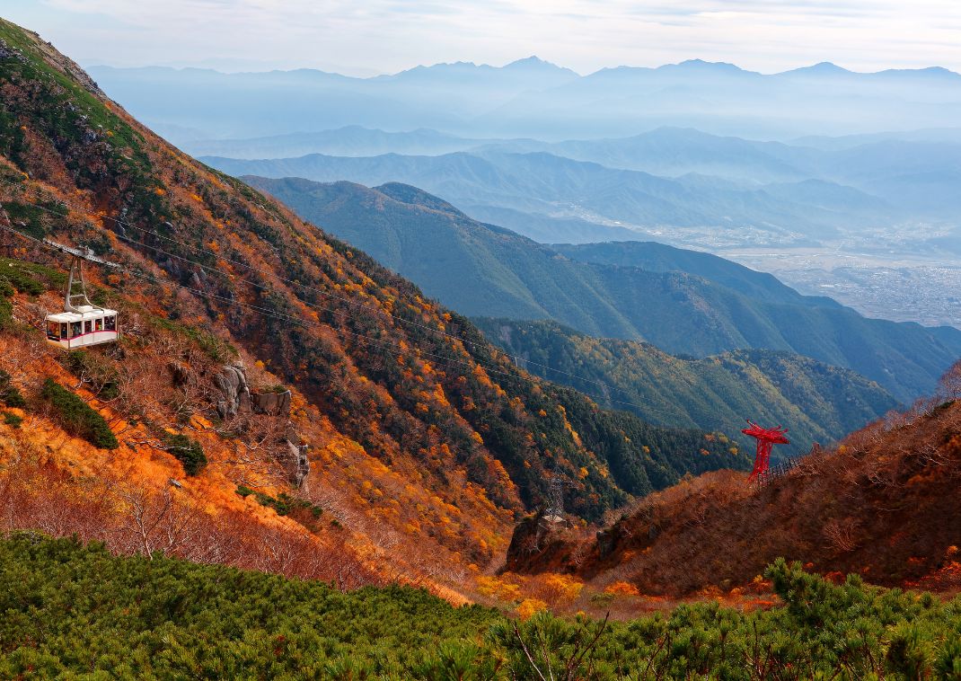 A cable car gliding over fall colours on the Kiso Mountain range up to Senjojiki Cirque, Japan