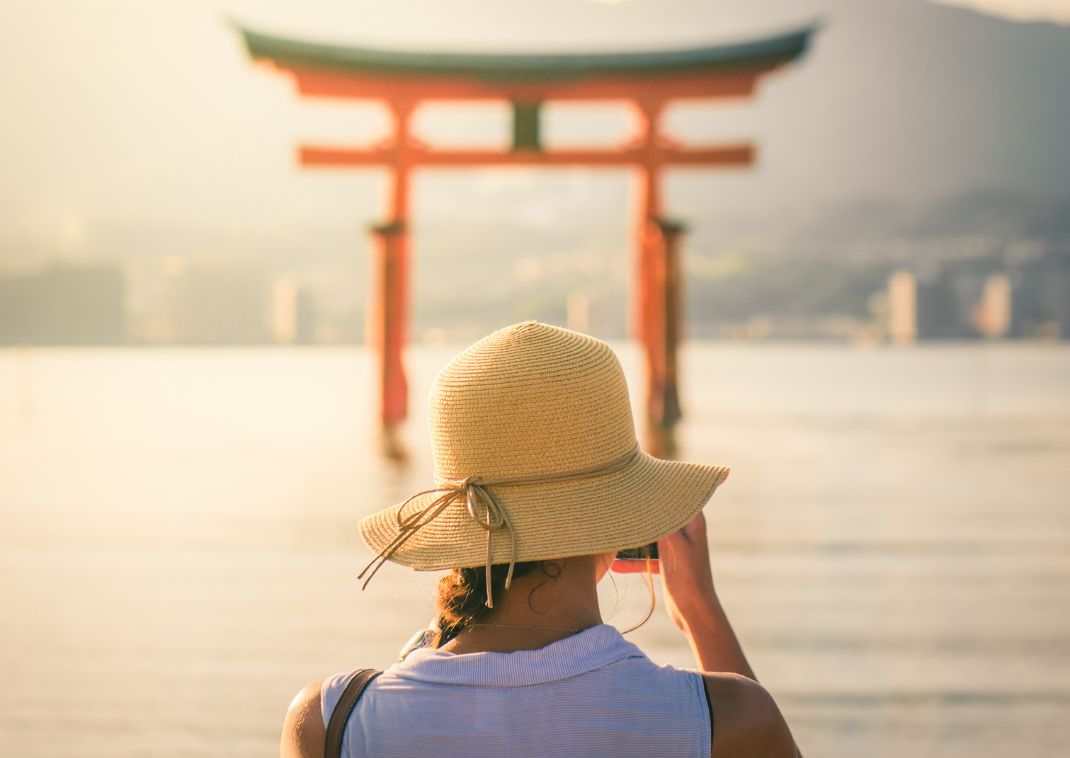 Pige fotograferer solnedgang ved Miyajima Island, Japan