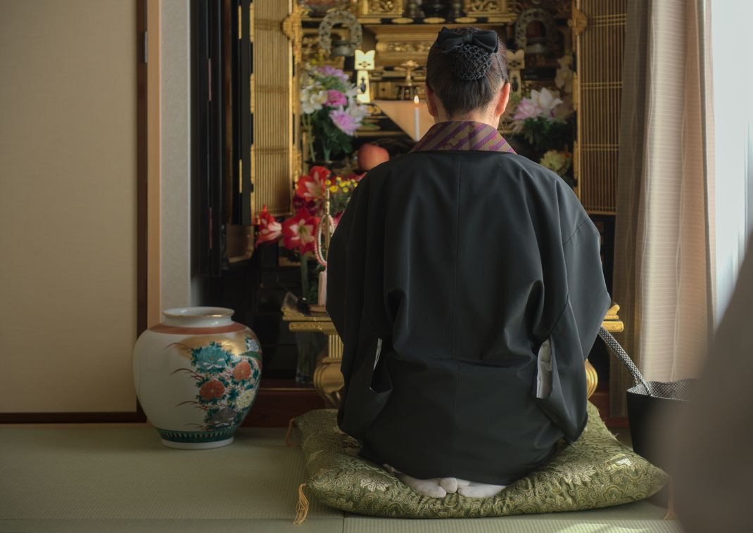 Japansk kvindelig buddhistisk munk fremsiger en bøn foran en Butsudan.
