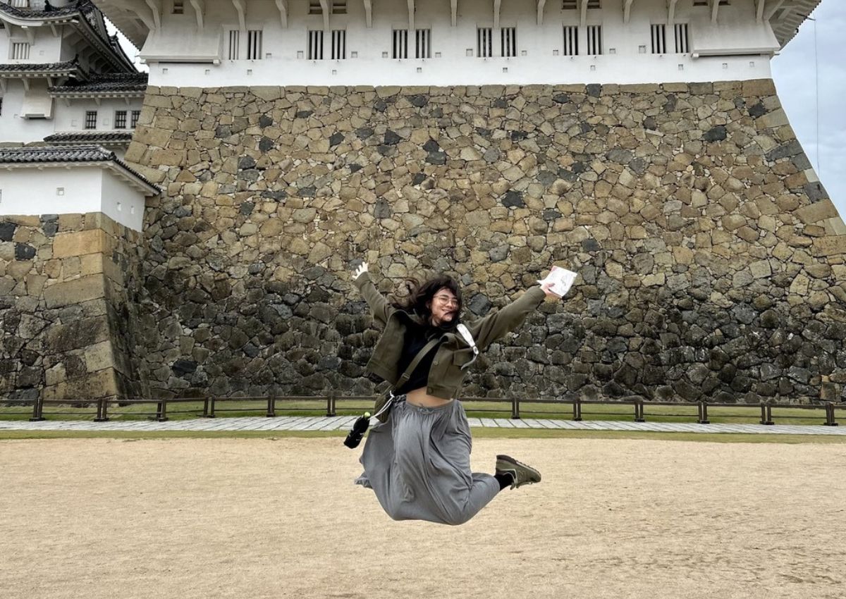 Ambre Taga foran den hvide Himeji-borg i Japan.