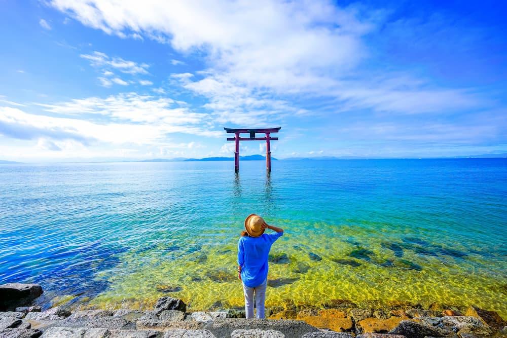 Rejsende står nær en torii-port ved Biwa-søen i Shiga Prefecture, Japan