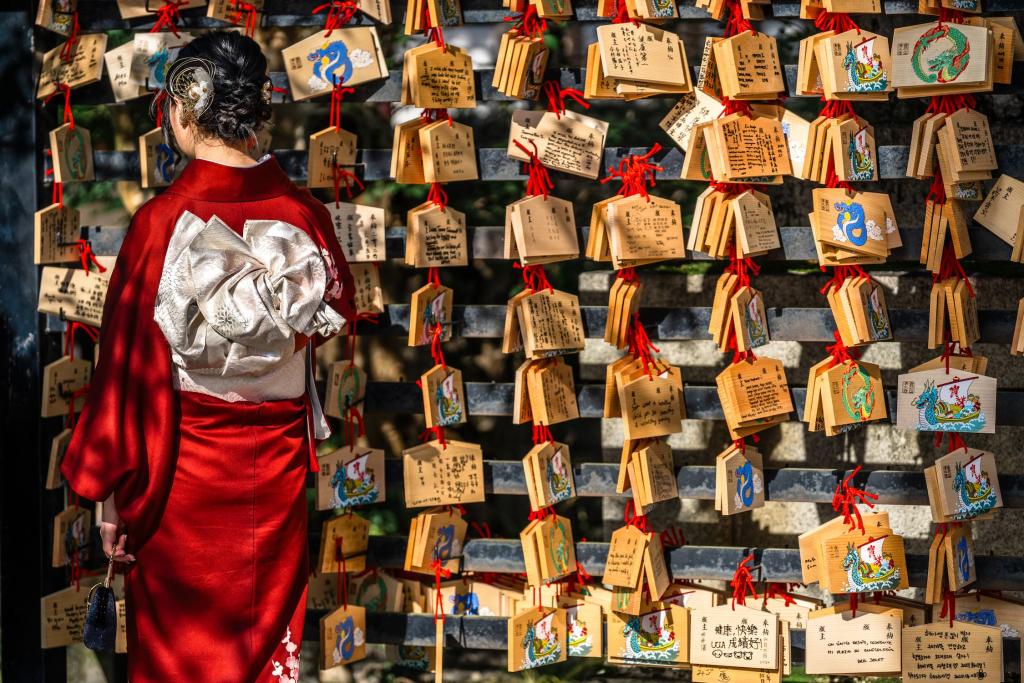 Japansk kvinde læser bedekort på en træplade i Kiyomizu-dera-templet i Kyoto