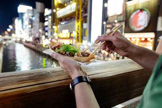 En mand spiser takoyaki, Osaka