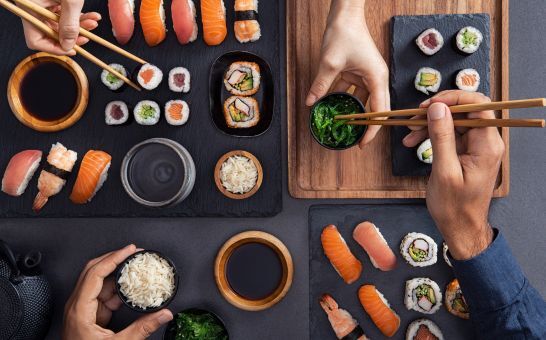 Assorteret sushi, herunder nigiri, sashimi og ruller, der deles og spises med pinde