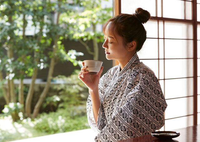 Ung kvinde nyder en kop te på en traditionel ryokan