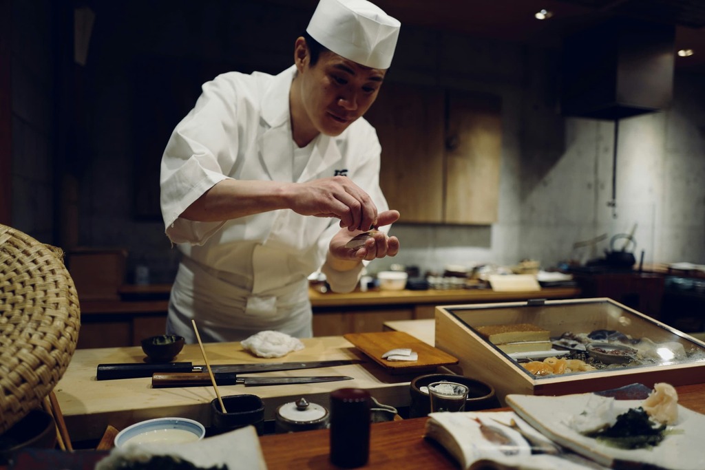 Japansk kok laver sashimi foran bardisken på en japansk sushirestaurant