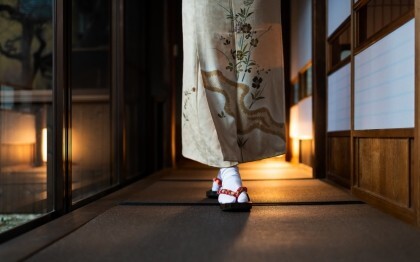 Kvinde i kimono går gennem en traditionel ryokan med tatamimåtter og shoji-døre