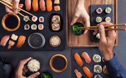 Assorteret sushi, herunder nigiri, sashimi og ruller, der deles og spises med pinde