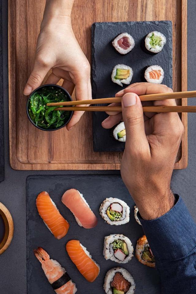 Assorteret sushi, herunder nigiri, sashimi og ruller, der deles og spises med pinde
