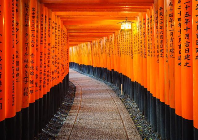 En traditionel rød japansk torii-port med sorte skrifttegn, Fushimi Inari-helligdommen, Kyoto, Japan