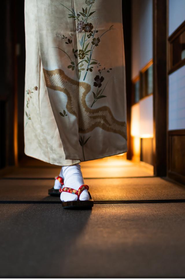 Kvinde i kimono går gennem en traditionel ryokan med tatamimåtter og shoji-døre